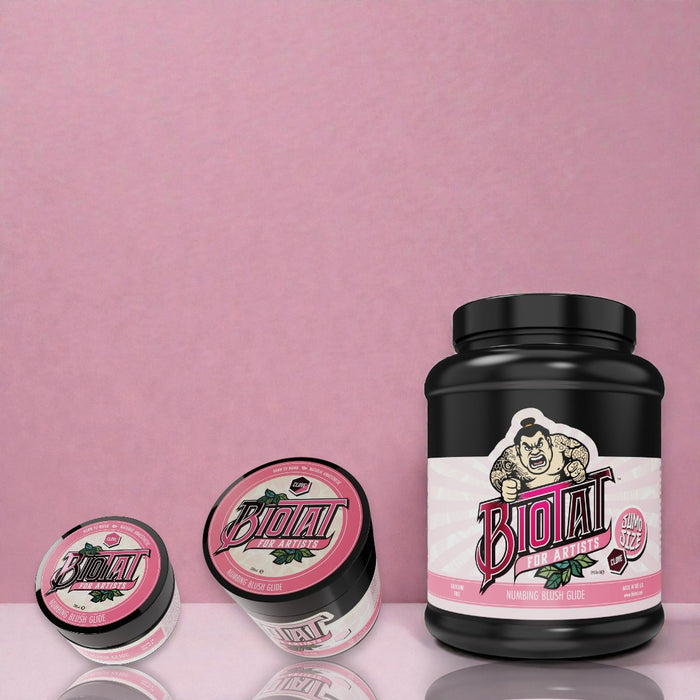 Biotat Glide Blush tattoo glide jars in multiple sizes displayed on a matte studio surface with blush-toned background